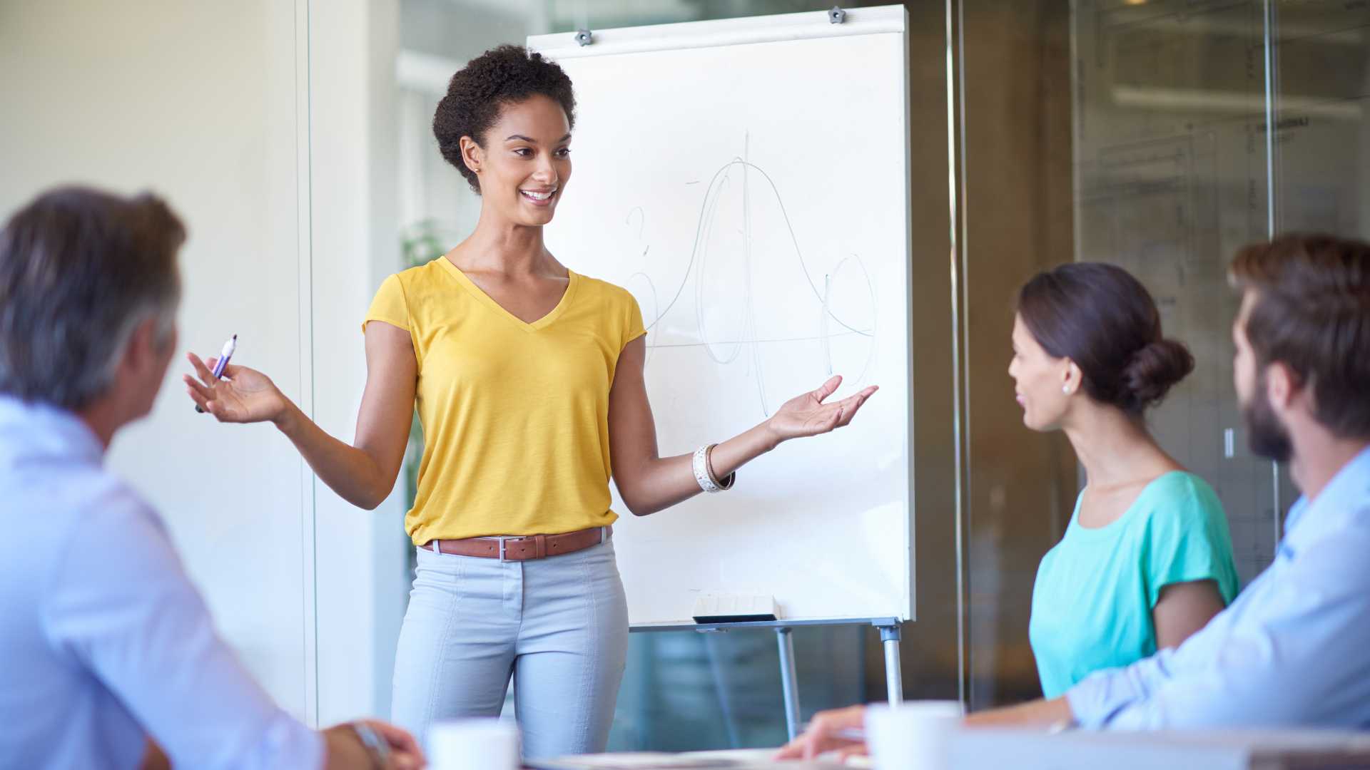 Jeune femme devant un tableau en train de faire un pitch